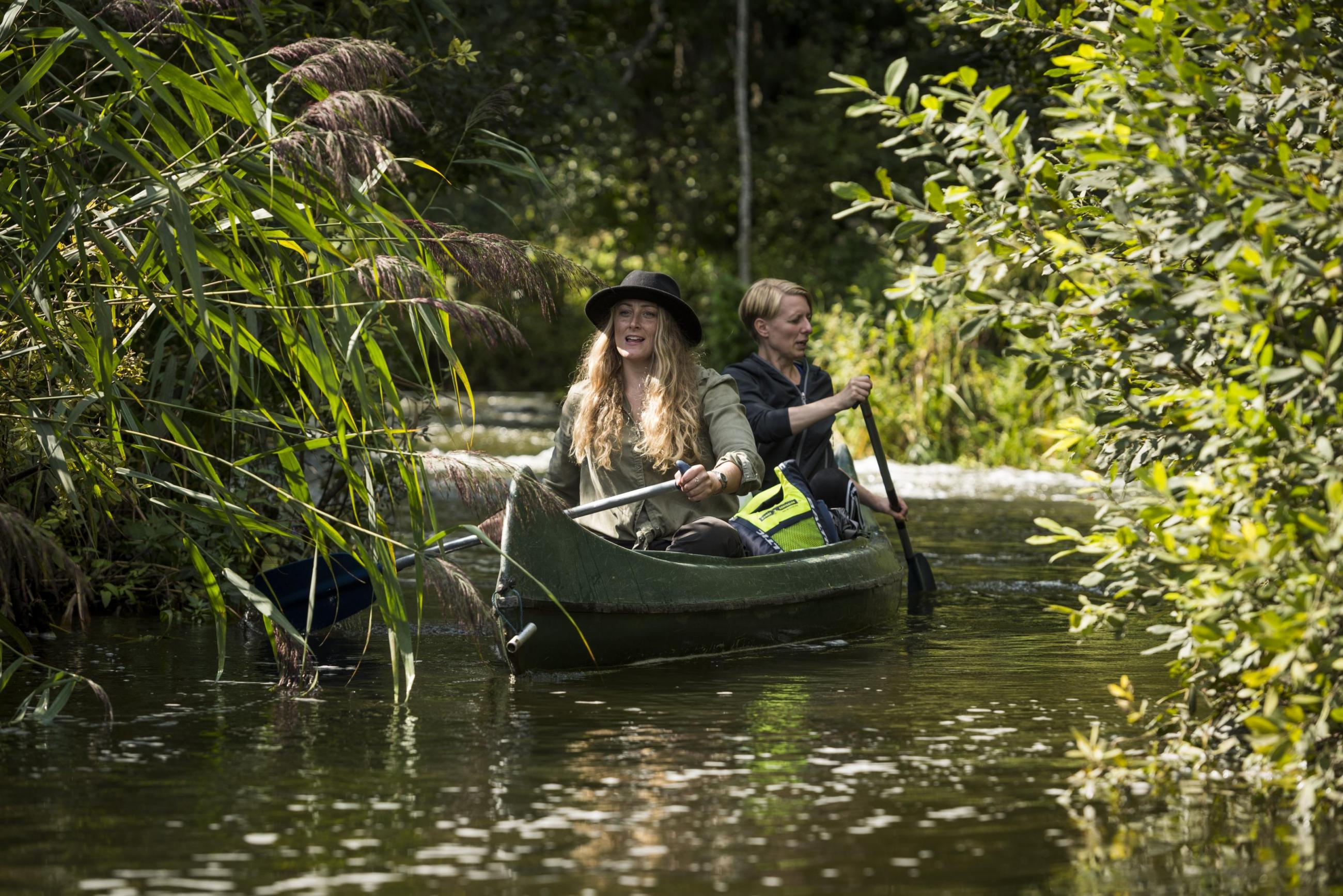Two women canoeing on a river.