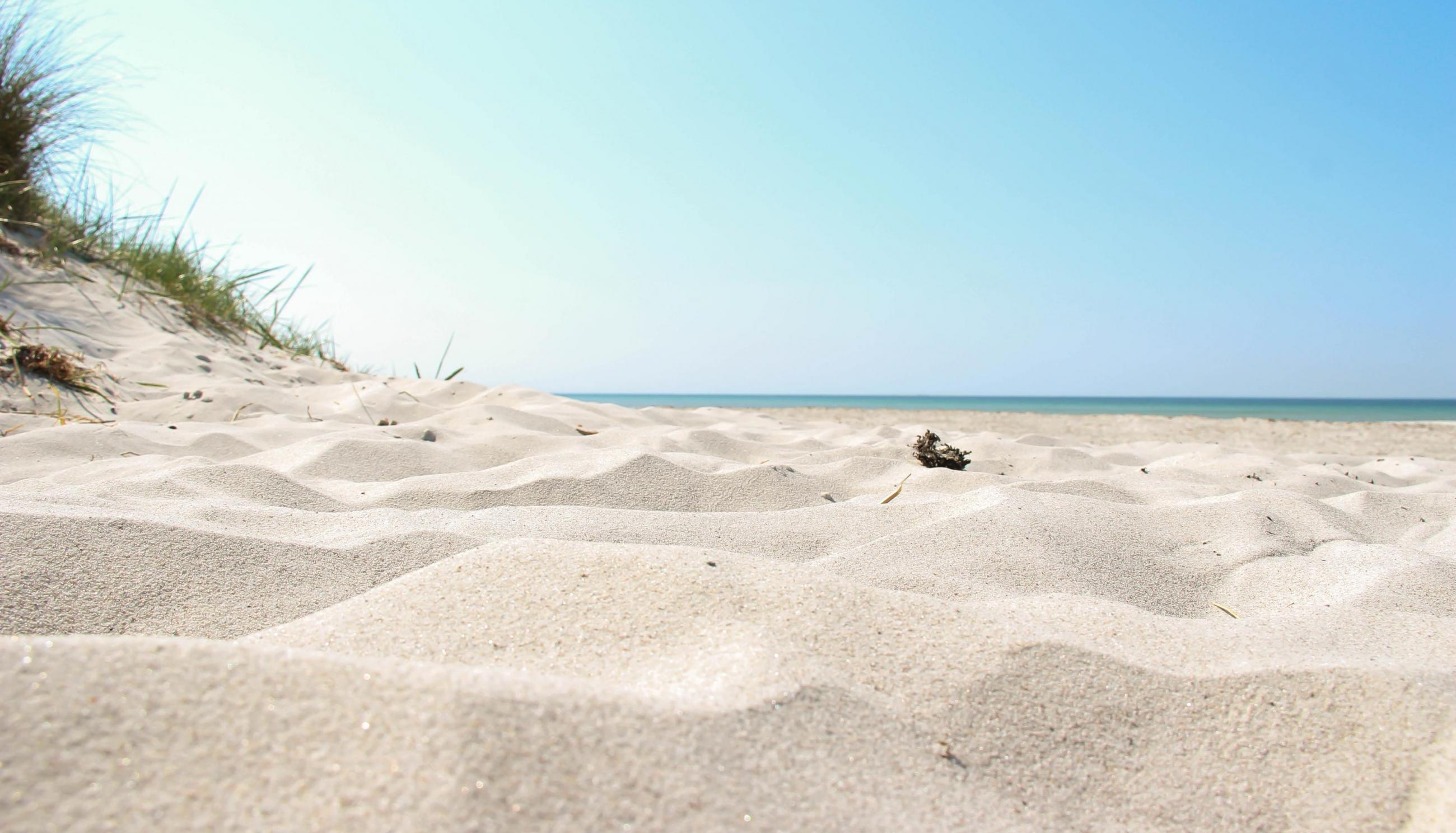 En vit sandstrand i Sandahmmar på en klar sommardag
