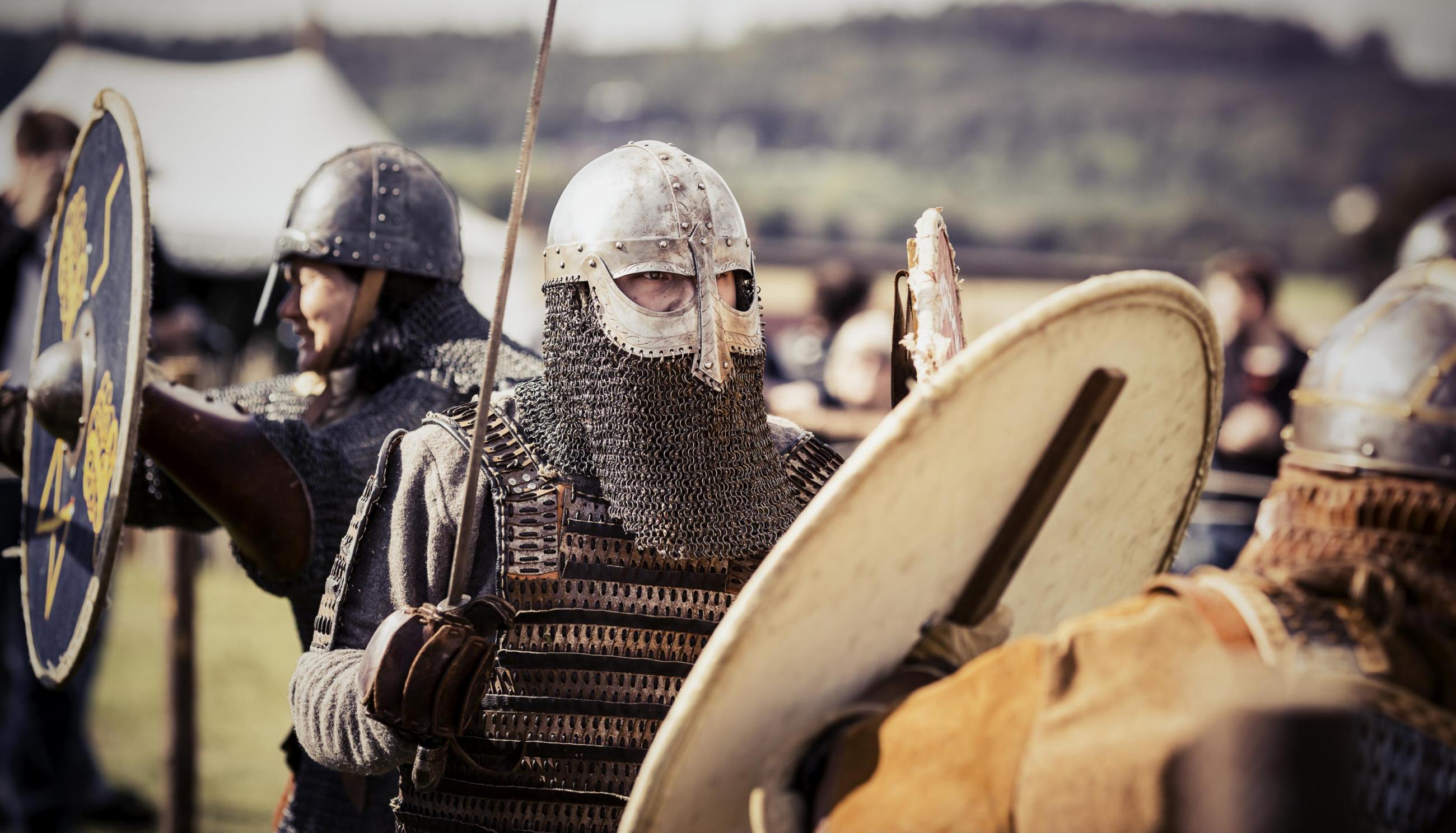 Vikingar med svärd och rustning i en vikingby