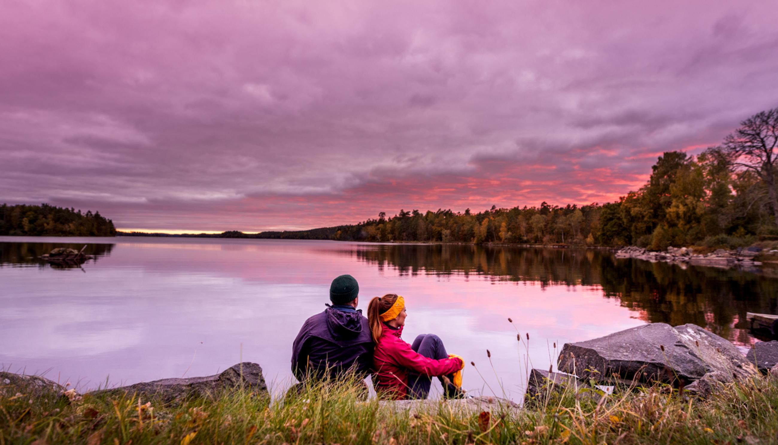 Ett par sitter intill Immeln sjön och tittar på solnedgången