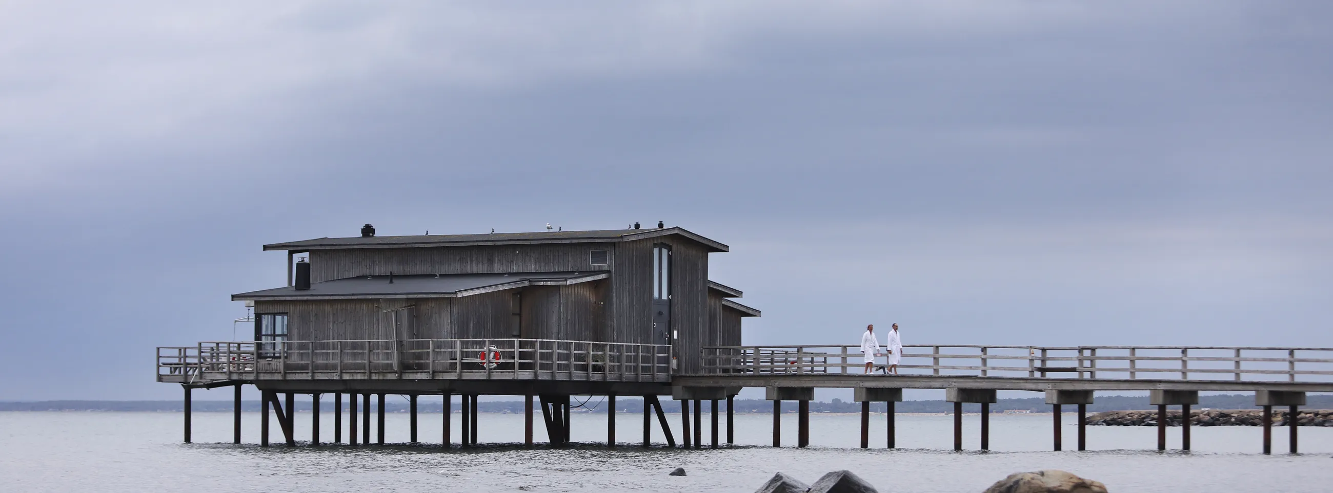 Land view of open-air bathhouse held up by pier stilts in the sea