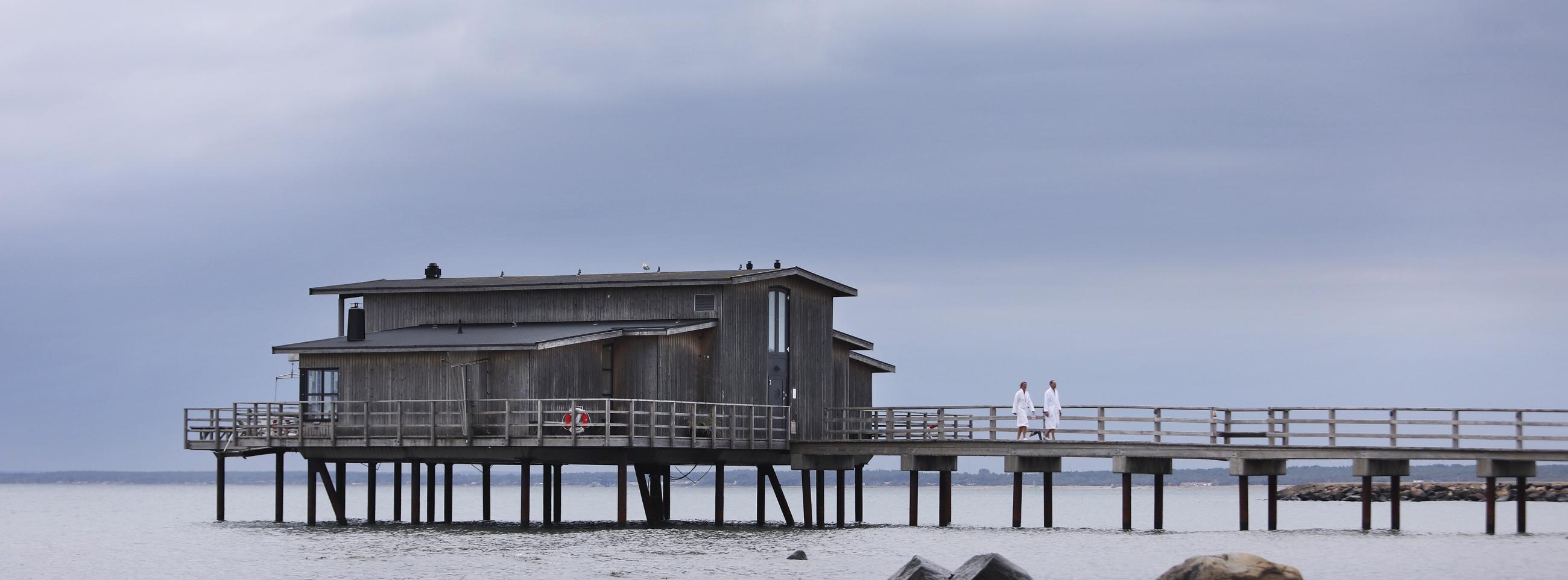 Land view of open-air bathhouse held up by pier stilts in the sea