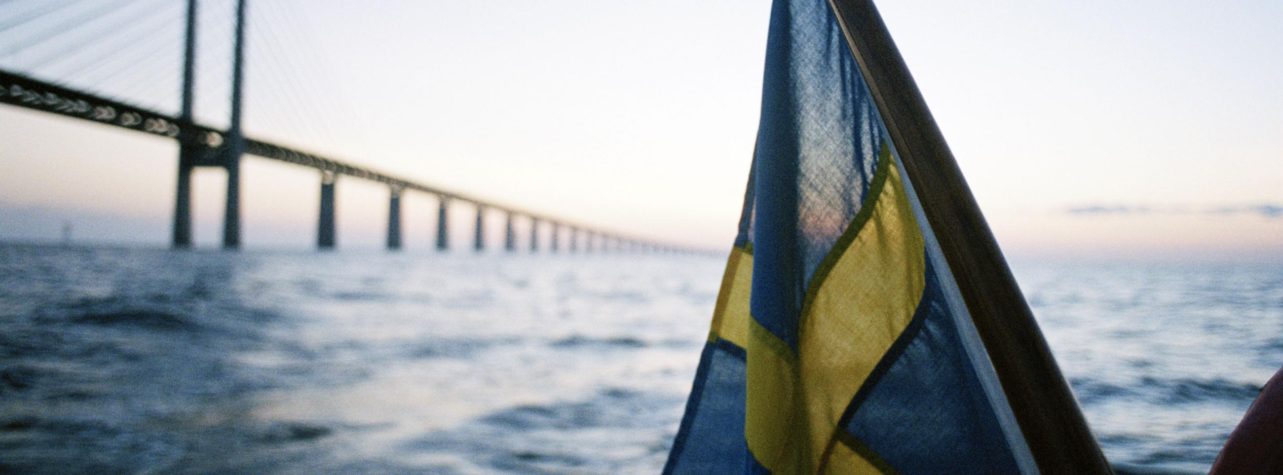 Swedish flag in front of the Öresund Bridge taken from the sea