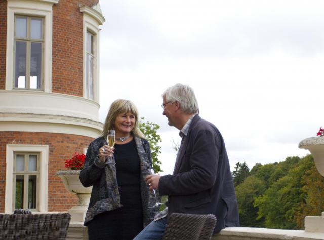 A couple enjoy a glass of champagne on a balcony at Häckeberga castle