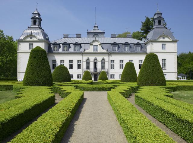 A boxwood garden maze with the fairytale Kronovalls chateaux in the background