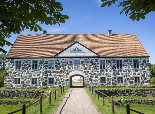 white and black castle building made of stone with a walking path that passes through