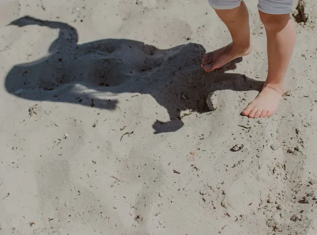 Ein steht Kind an einem Sandstrand in Skåne.