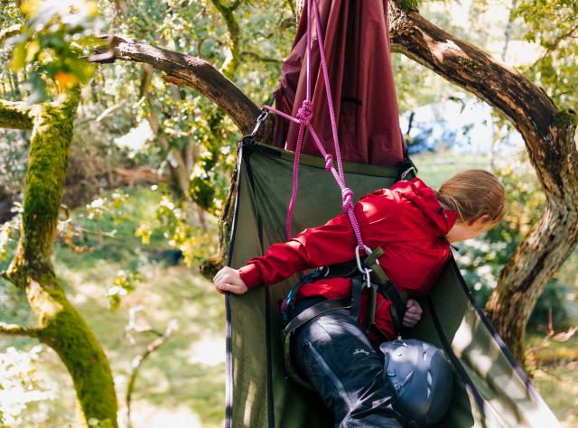 Ein Mädchen klettert aus einer Hängematte im Klettergarten Embla Träd in Fulltofta.