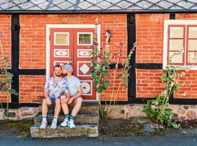 Couple of men sitting in a staircase souronded by flowers in Kivik