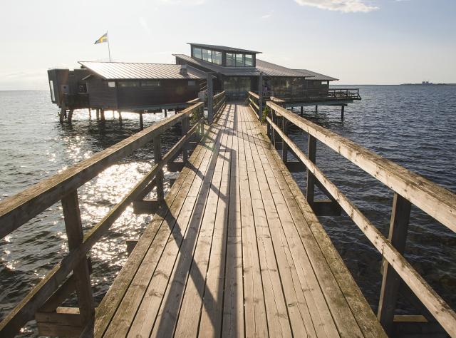 Pier leading to open-air bathhouse surrounded by sea 