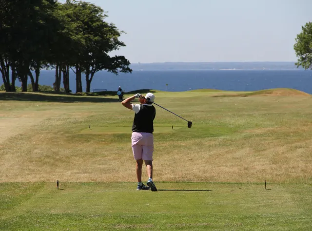 Golfer swinging his bat towards the sea 