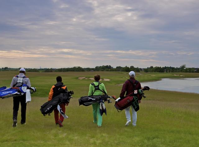 Four golfers walking on golf field
