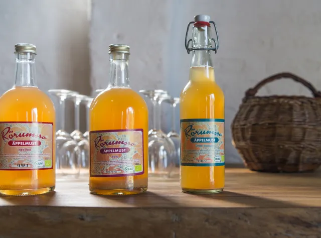 Apple juice bottles in a row with woven basket in the background