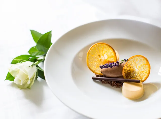 Gourmet food on plate with a white flower next to it at Bjärsjölagårds castle