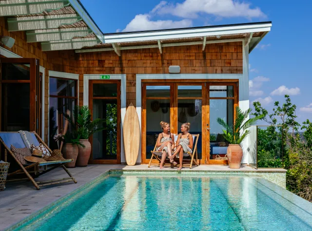  Two women relaxing in sun chairs by a pool