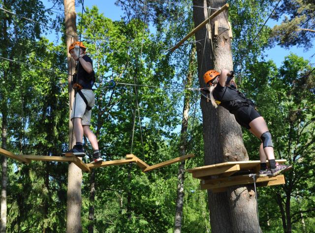 Två personer går på en höghöjdsbana mellan träd