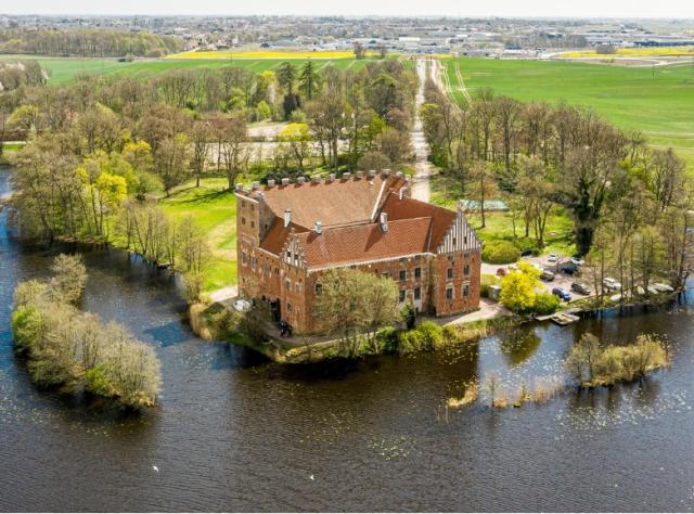 Castle seen from above on a peninsula surrounded by water with farmland behind
