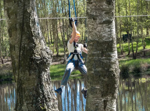 A child going on a zipline in between trees