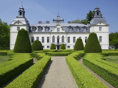 En labyrintträdgårds av buxbom med det sagolika Kronovalls slott i bakgrunden