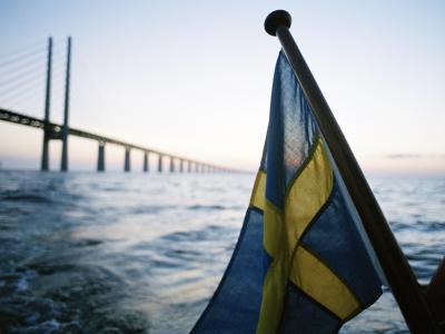 Swedish flag in front of a large bridge in the background