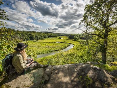 A woman siting on a Cliff overlooking a green valley