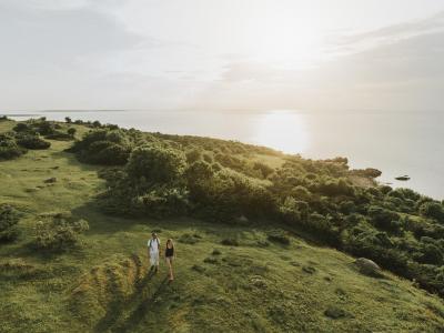 Hovs Hallar from above Ett par fotvandrar på ett grönt landskap med havet i bakgrunden i Hovs Hallar