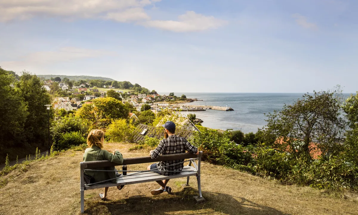Couple on a bench ovelooking a village by the sea