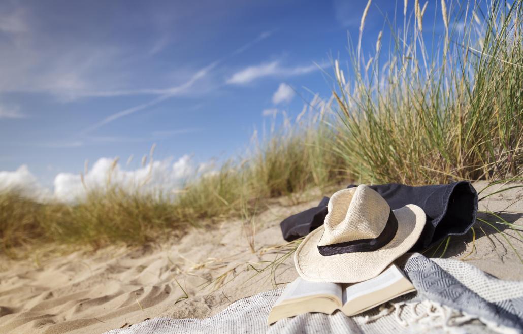 hatt som ligger på en handduk på en sandstrand